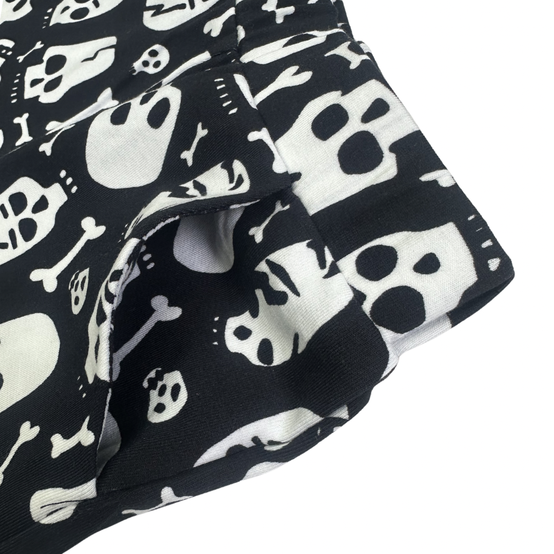 Black and white cotton shorts with a skull and bone print, featuring an elasticated waistband and side pocket.